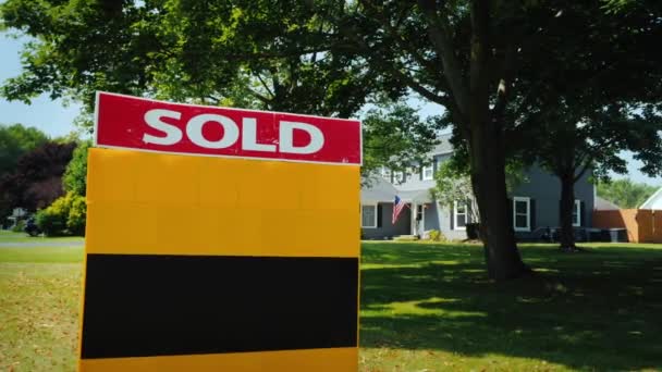 Тарелка со словами Продано, на заднем плане типичный американский дом с флагом США — стоковое видео