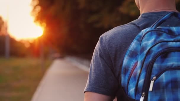 Een tiener met een rugzak loopt langs de weg naar school, alleen zijn schouder en een deel van de rugzak zijn zichtbaar in het frame — Stockvideo