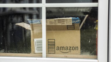 Wilson, New York, ABD, Temmuz 2019: İçinde Amazon logosu olan paketten açık bir kutu pencerenin dışında görünüyor.
