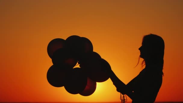 Silhueta de uma mulher com balões ao pôr-do-sol. Conceito de inspiração e criatividade — Vídeo de Stock