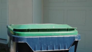 Ev hanımı evin yakınındaki tanka çöp torbası atıyor