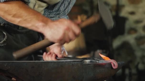 Mano de un herrero con un martillo, hace un producto forjado golpeando el yunque. Artesanía antigua — Vídeos de Stock