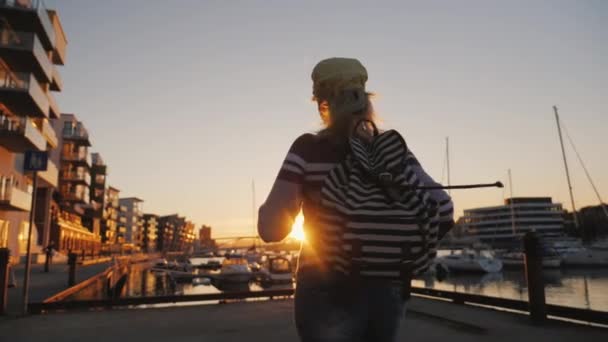 Actieve vrouw verheugt zich bij zonsopgang over de jachthaven. Loopt naar voren, steekt zijn handen omhoog. Zonsopgang in Bergen — Stockvideo