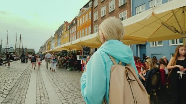 Kodaň, Dánsko, červenec 2018: žena, která se prochází po kanálu Nyhavn, na pozadí slavných barevných domů. Nejoblíbenější místo mezi turisty je Kodaň, Dánsko — Stock video