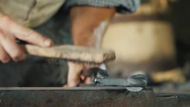 Metal fırçalı bir demirci, iş parçasını kireç ve enkazdan temizler. Esnaf işçiliği