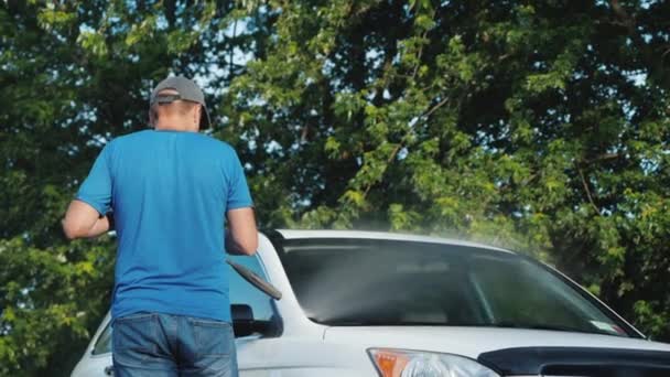男は裏庭で彼の車を洗う,後ろの景色 — ストック動画