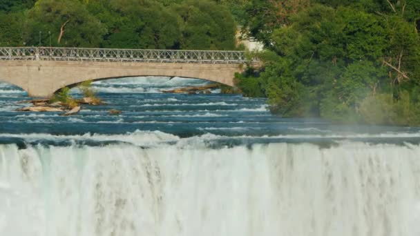 Niagara Şelalesi ve turistlerin yürüdüğü Niagara Nehri'nin karşısındaki köprü — Stok video