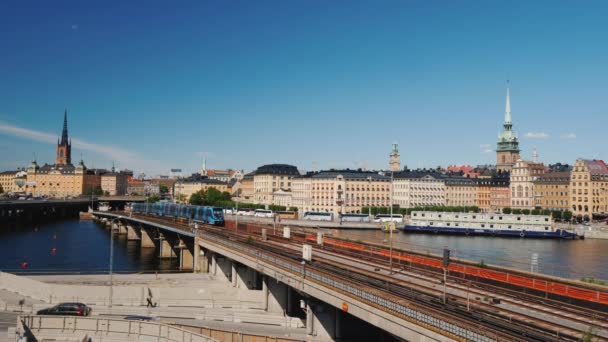 Поезд метро пересекает мост на фоне городской линии Стокгольма, Швеция — стоковое видео