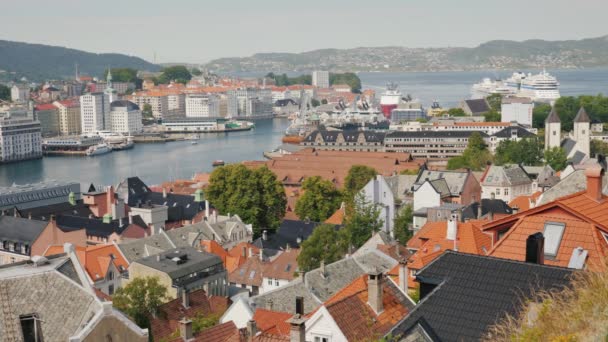 Bergen şehrinde yukarıdan bir görünüm, aşağıda bir yolcu gemisi ile eski evlerin çatıları ve koyun görünür — Stok video