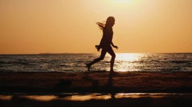 Sahilde koşan kaygısız bir çocuğun silüeti.