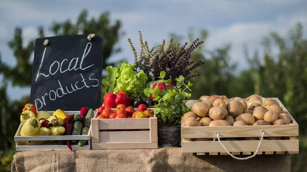 Outdoor shot of Counter with fresh vegetables and a sign of local products — Stock Photo, Image