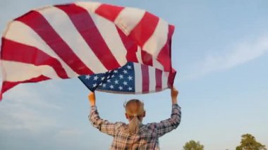 Elinde Amerikan bayrağıyla koşan bir kadın. Arka planda bayrak sallanıyor.