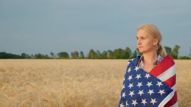 Kvinna bonde med usa flagga på ogräs promenader längs vete fält — Stockvideo