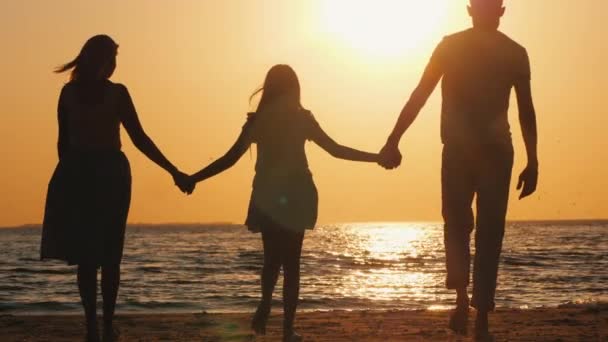 Familia con un niño va al mar al atardecer — Vídeo de stock