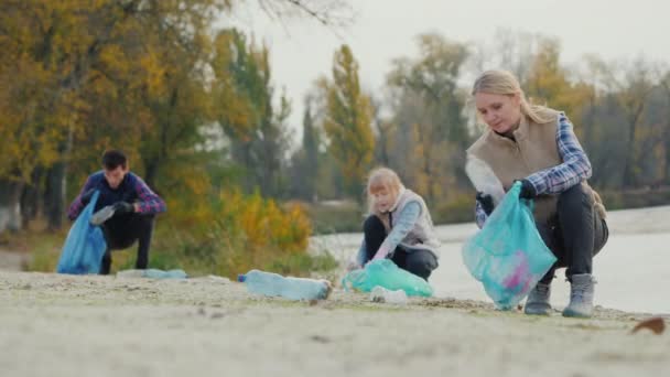 Η οικογένεια μαζεύει πλαστικά σκουπίδια από τη λίμνη. Έννοια καθαρού περιβάλλοντος — Αρχείο Βίντεο