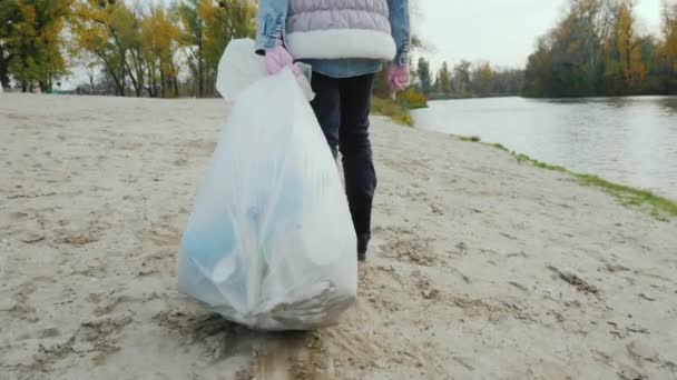 Gönüllü bir çocuk plaj boyunca ağır bir çöp torbasını sürüklüyor. Atık ve Aktivizmin Temizlenmesi — Stok video