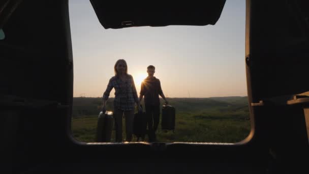 Мужчина и женщина кладут свой багаж в багажник внедорожника, готовясь к путешествию — стоковое видео