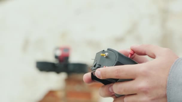 Hands of the pilot of the cinedrone with the control panel, in the background you can see a flying drop — Stock Video