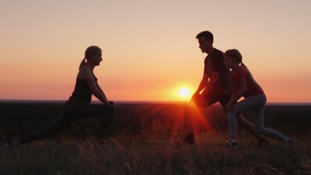 Familia con un niño haciendo ejercicios juntos en un lugar pintoresco al atardecer — Vídeos de Stock