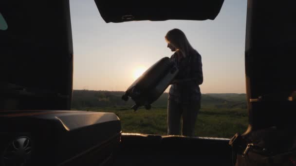 Een jonge vrouw laadt dingen uit de kofferbak van een auto. — Stockvideo