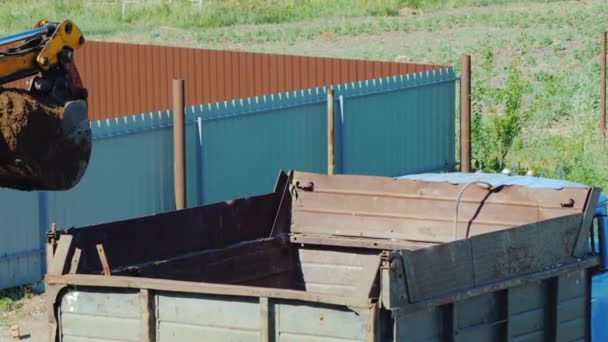 Vue de dessus du godet d'excavatrice déverse le sol dans le camion — Video