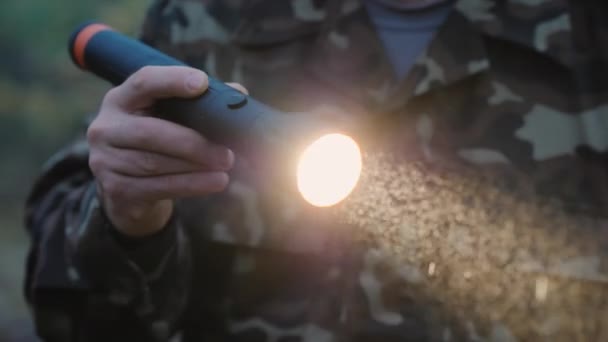 Uma mão com uma lanterna ilumina o caminho na floresta, gotas de nevoeiro são visíveis em um feixe de luz — Vídeo de Stock