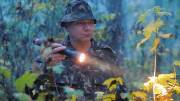 Ein Mann zündet in der Abenddämmerung im Wald eine Taschenlampe an. Suchaktion — Stockvideo