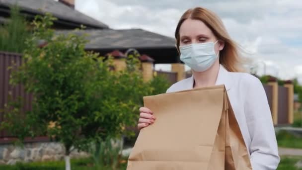 マスクの女性は彼女の家に食料を運ぶ — ストック動画