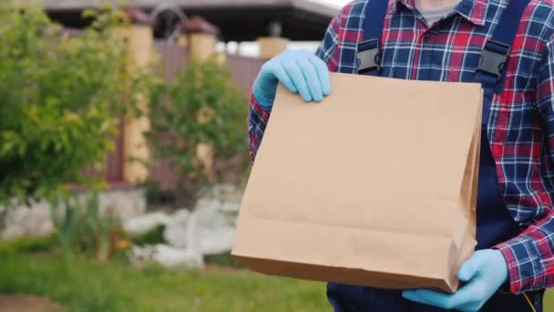 Ένας υπάλληλος της υπηρεσίας παράδοσης μεταφέρει σακούλες τροφίμων στο σπίτι των πελατών — Αρχείο Βίντεο
