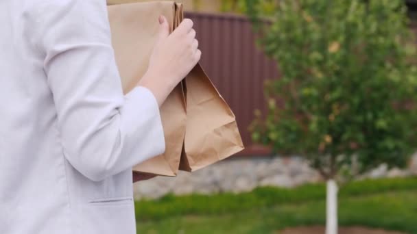 Zadní pohled: Mladá žena nese tašky s potravinami k sobě domů — Stock video