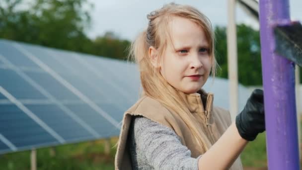 Un enfant peint des poteaux dans une centrale solaire domestique — Video