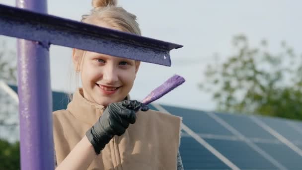 Un enfant peint des poteaux dans une centrale solaire domestique — Video