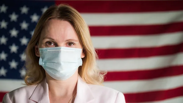 Retrato de una mujer de un hombre de negocios con una máscara protectora en el fondo de la bandera de Estados Unidos — Foto de Stock