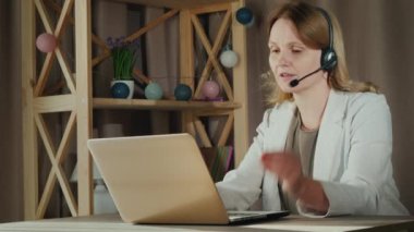 Kadın evden gelen müşterilerle iletişim kuruyor, kulaklıkla konuşuyor. Merkez Ofis