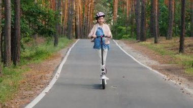 Kız parka giderken elektrikli scooter kullanıyor.