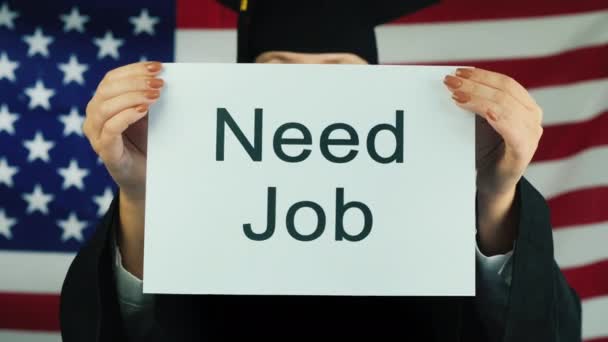 Absolwent w płaszczu i czapce trzyma plakat Need Job. Zatrudnienie w USA — Wideo stockowe