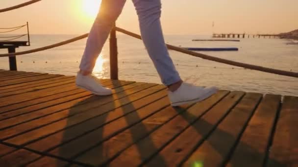 The woman walks along the pier in the early morning, in the frame only the legs can be seen — Stock Video