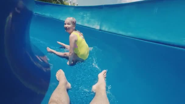 Chica alegremente huye de su padre en un tobogán acuático — Vídeos de Stock