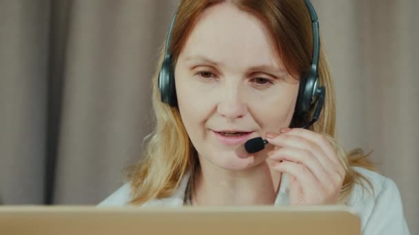 Porträtt av en kvinna som kommunicerar genom ett headset. Arbete hemifrån koncept — Stockvideo