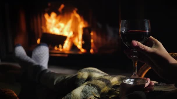 Masquer sous une couverture près de la cheminée avec un verre de vin à la main. Concept d'évasion hivernale — Video