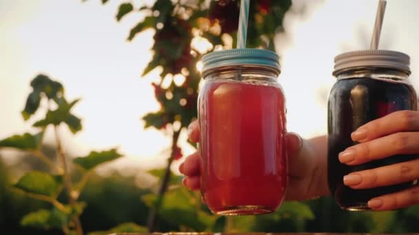 Uma mulher põe dois refrigerantes de frutas na mesa. Contra o pano de fundo do arbusto de groselha — Vídeo de Stock