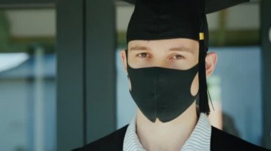 Koruyucu maske ve şapkayla mezun olmuş, kolejden karantina altında mezun olmuş.