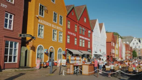 Bergen, Νορβηγία, Ιούλιος 2018: Ένας δρόμος με διάσημα ξύλινα σπίτια στο Μπέργκεν, δίπλα σε καλοκαιρινά καφέ, όπου ξεκουράζονται πολλοί τουρίστες — Αρχείο Βίντεο