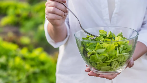 Donna snella mangia insalata, si trova vicino al suo letto dove è cresciuto — Foto Stock