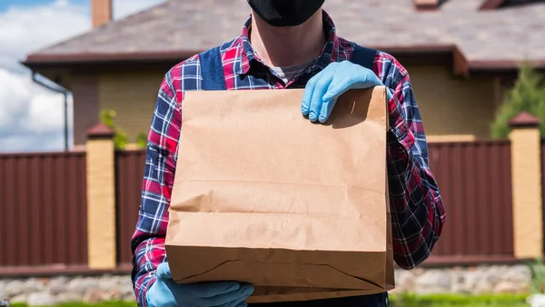 장갑 과 마스크를 쓴 전령은 식료품이 담긴 가방을 들고 있다 — 스톡 사진