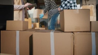 Teslimat işçileri bir arabanın bagajına kutular yükler.