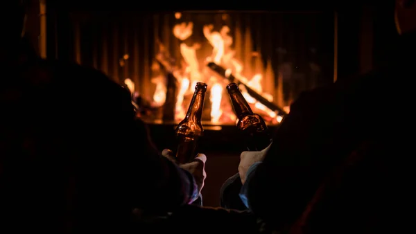 Fuga de inverno - os amigos relaxam junto à lareira com cerveja nas mãos — Fotografia de Stock