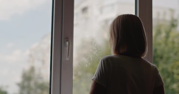 Uma mulher lava uma janela no apartamento de um prédio alto. — Vídeo de Stock
