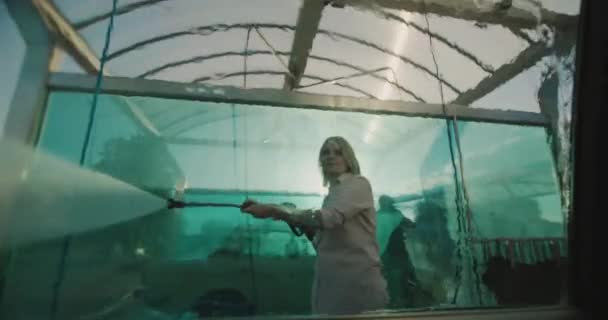 Uma mulher lava seu carro em uma pia de auto-atendimento, vista de dentro do carro — Vídeo de Stock
