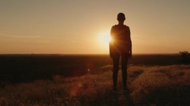 Gün batımında duran bir sporcunun silueti, güneş vücudunu aydınlatır..